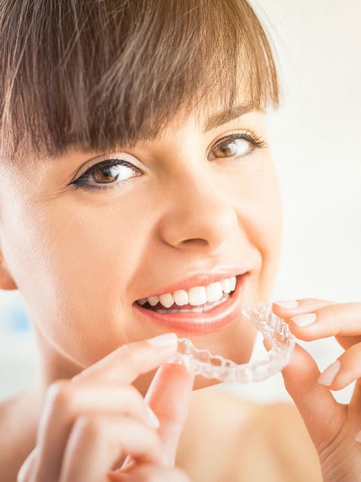 Woman about to insert invisalign brace.