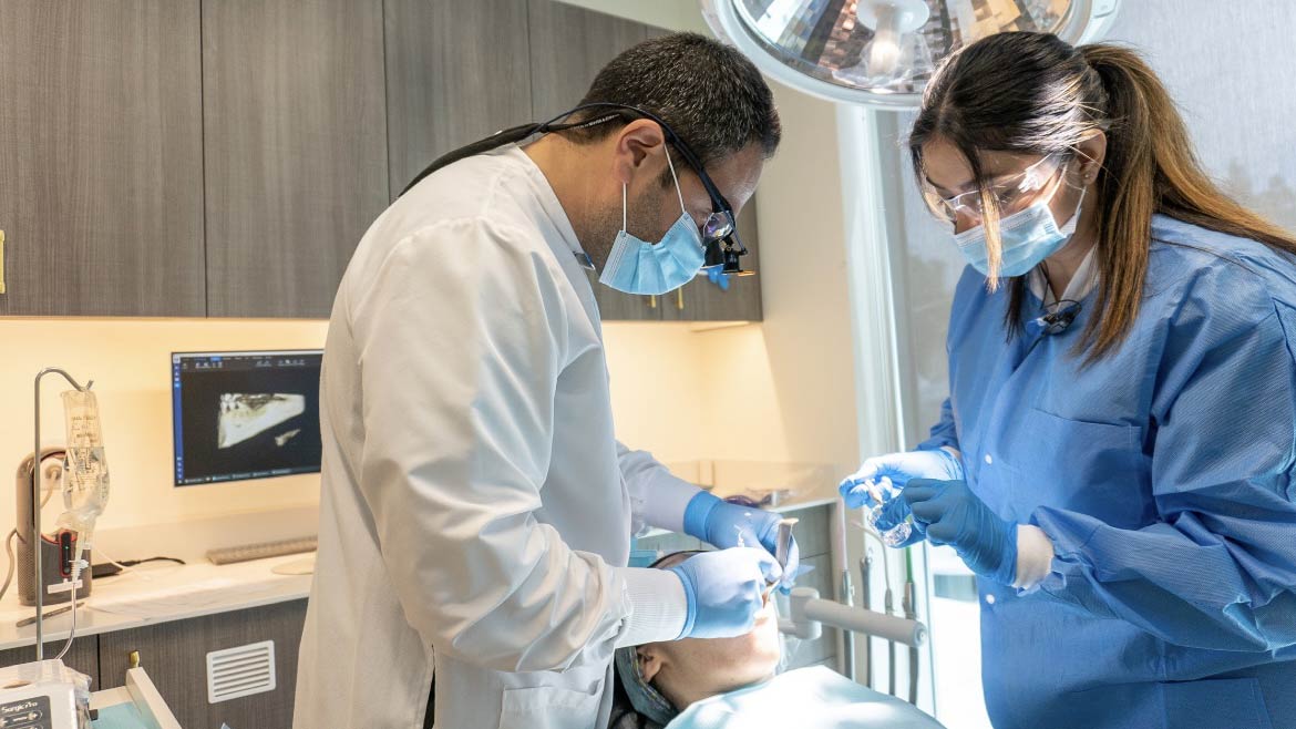 A dentist and assistant are working on a patient's teeth.