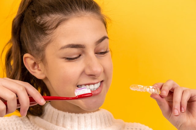 Girl holding a toothbrush getting ready to clean her invisalign clear aligner in Santa clarita ca.