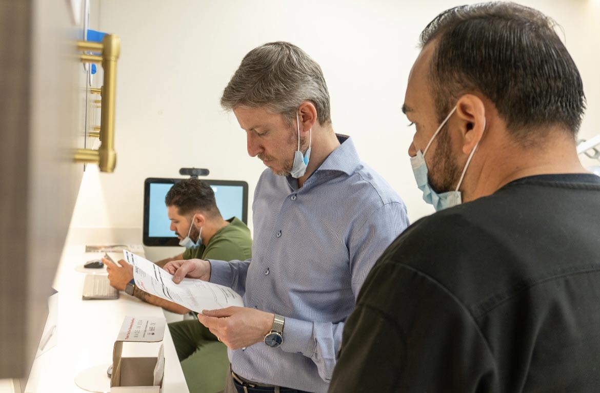 A dentist and his assistant are looking at a patient's x-ray.